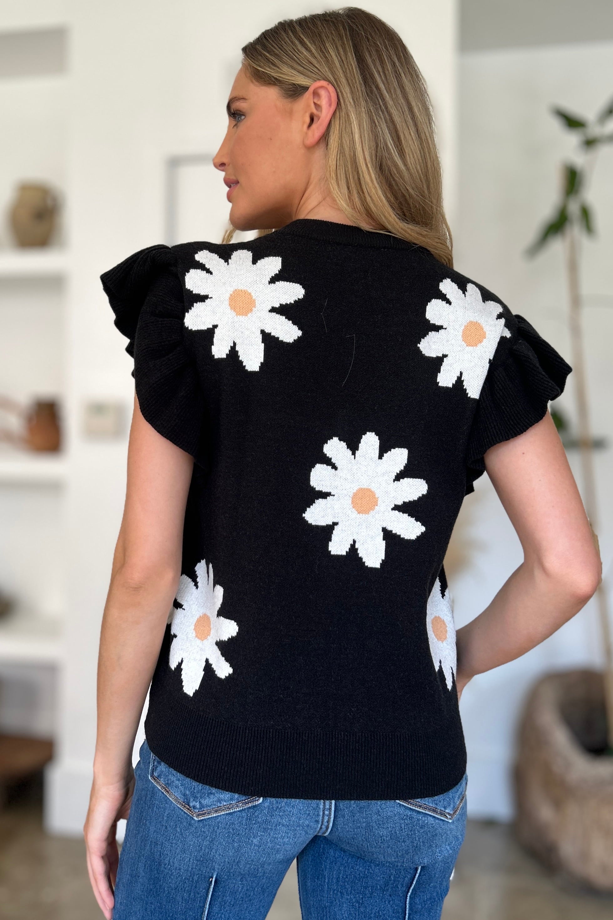 Black knit top with daisy pattern and ruffle sleeves