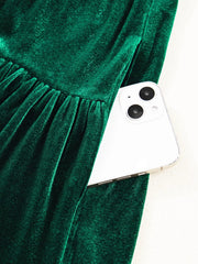 Dark green velvet mini dress with tiered skirt and hidden pocket holding a smartphone.