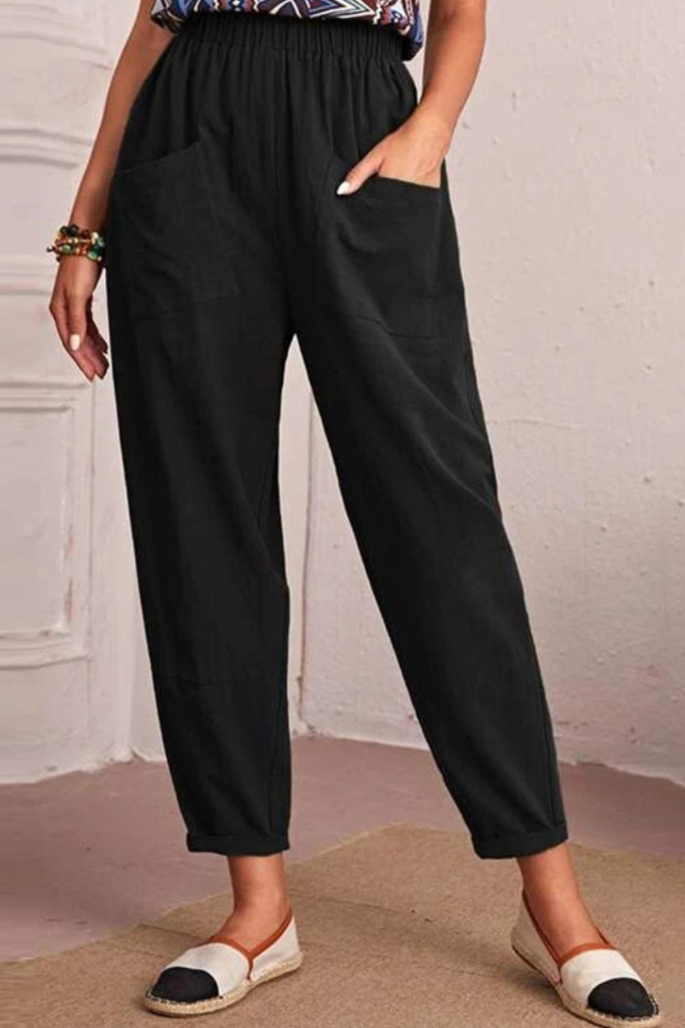 Black linen tapered trousers with elastic waist and large front pockets.