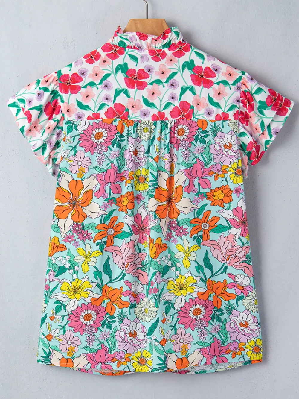 Maternity overshirt with flutter sleeves and a ruffled neckline in a vibrant floral print.