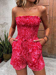 Smocked bandeau romper in strawberry print with tie waist and ruffle trim.