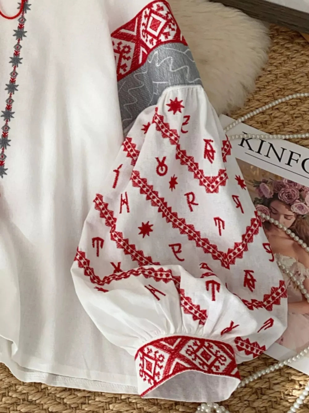 White embroidered folk shirt with red and grey details on the sleeve and neckline.