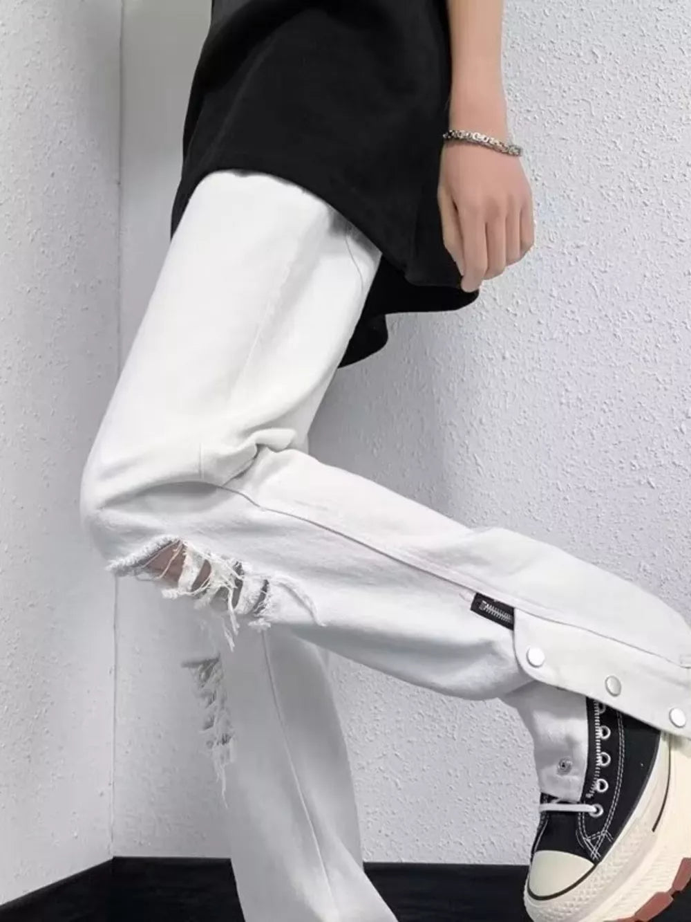 White distressed loose-fit jeans with snap detail and adjustable hem.