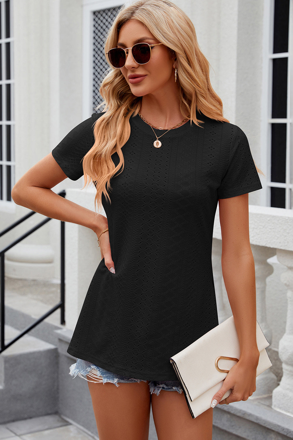 Black crewneck top with allover perforation and short sleeves, styled with denim shorts.