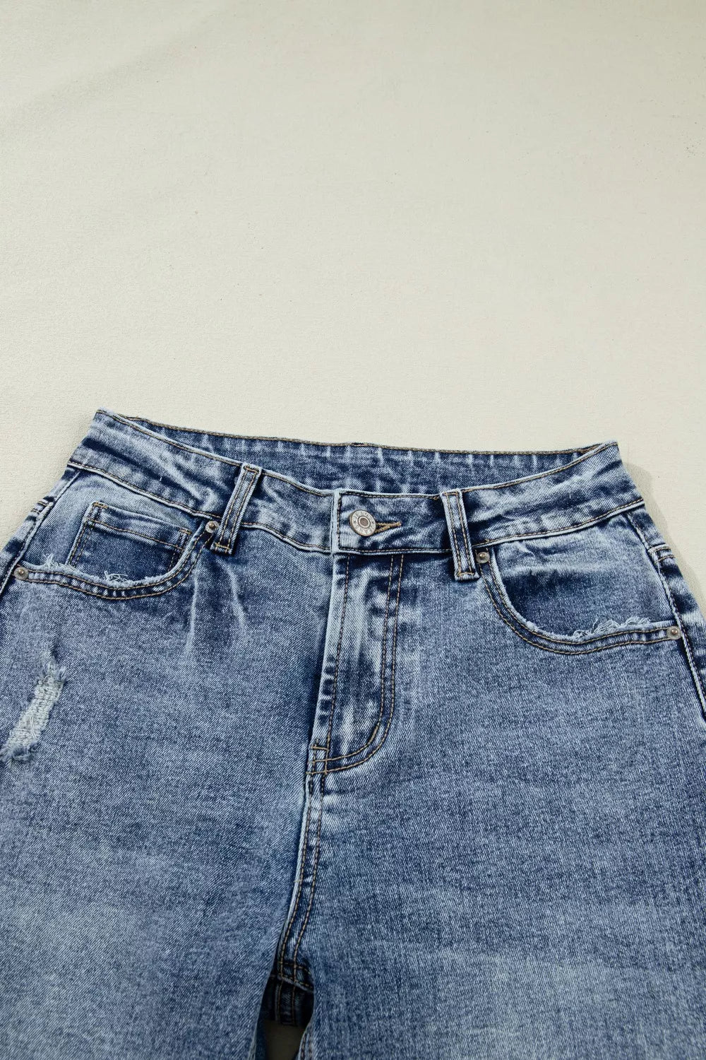 Cuffed mid-rise relaxed fit jeans in distressed blue denim with pocket details.