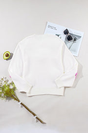 White knit sweater with embroidered pink blooms on the sleeves and a crew neckline.