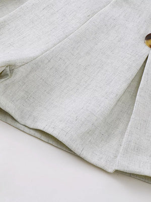 Light grey linen-blend baby vest and shorts set detail, showing button closure.