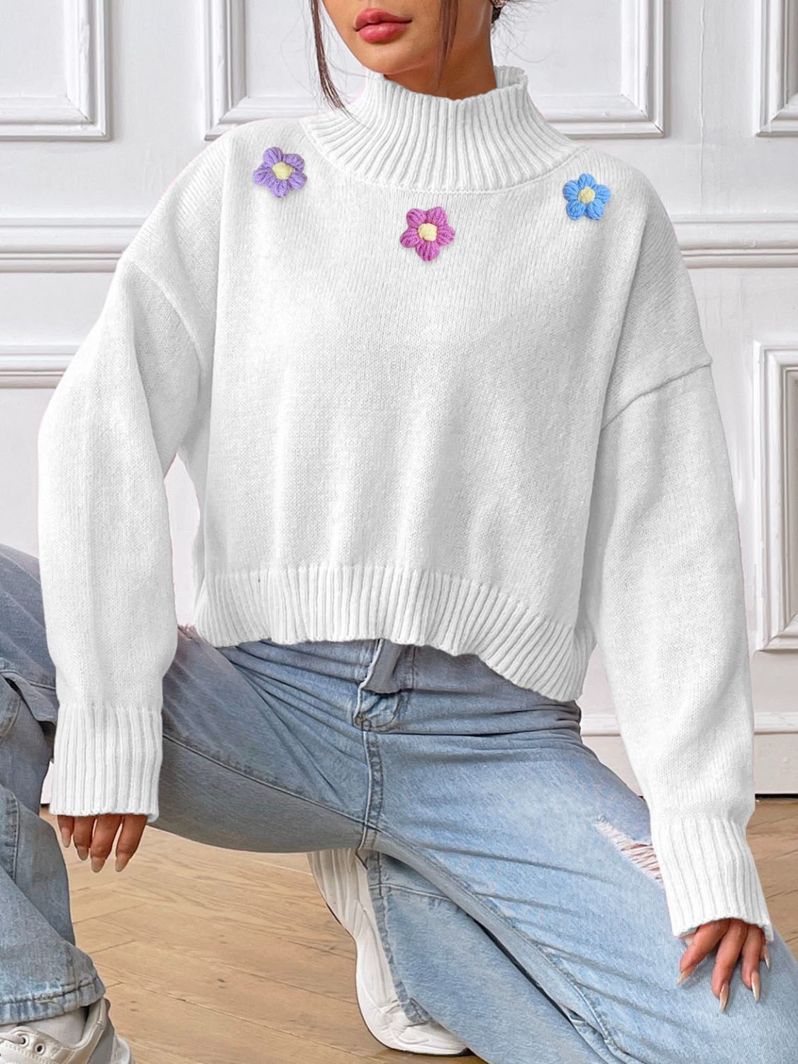 White cropped turtleneck knit sweater with embroidered floral details.