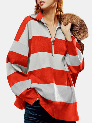 Oversized knit pullover with bold orange-red and gray stripes, quarter zip neckline, and ribbed cuffs and hem.