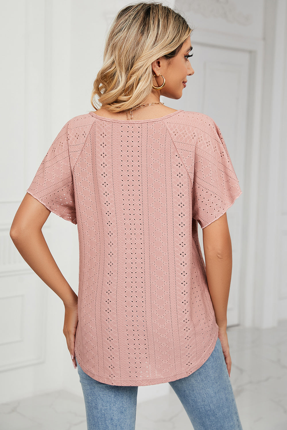 Pink eyelet blouse with flutter sleeves and a scoop neckline.