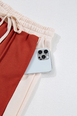 Terracotta and cream panel track pants with drawstring waist and phone pocket detail.