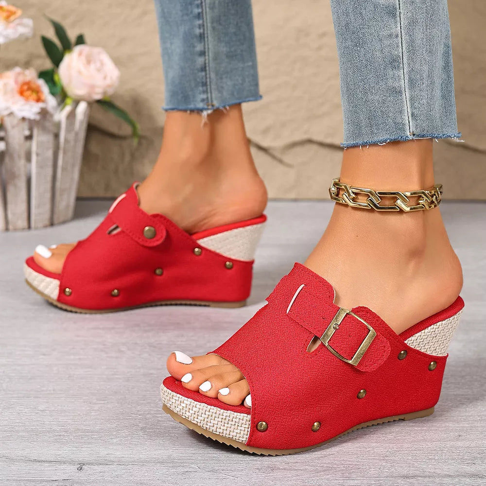 Red wedge sandals with decorative accents and buckle detail.