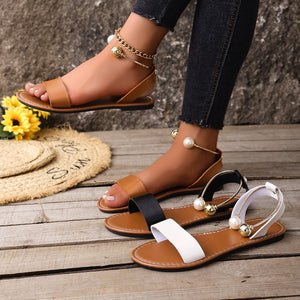 Elegant open-toe sandals with pearl and gold ball ankle straps in brown, black, and gray/white.