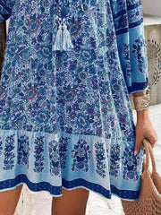 Light blue floral mini dress with tassel tie neckline and tiered hem.