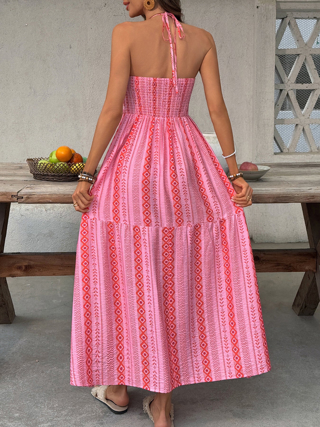 Pink halter neck midi dress with geometric print and tiered skirt.