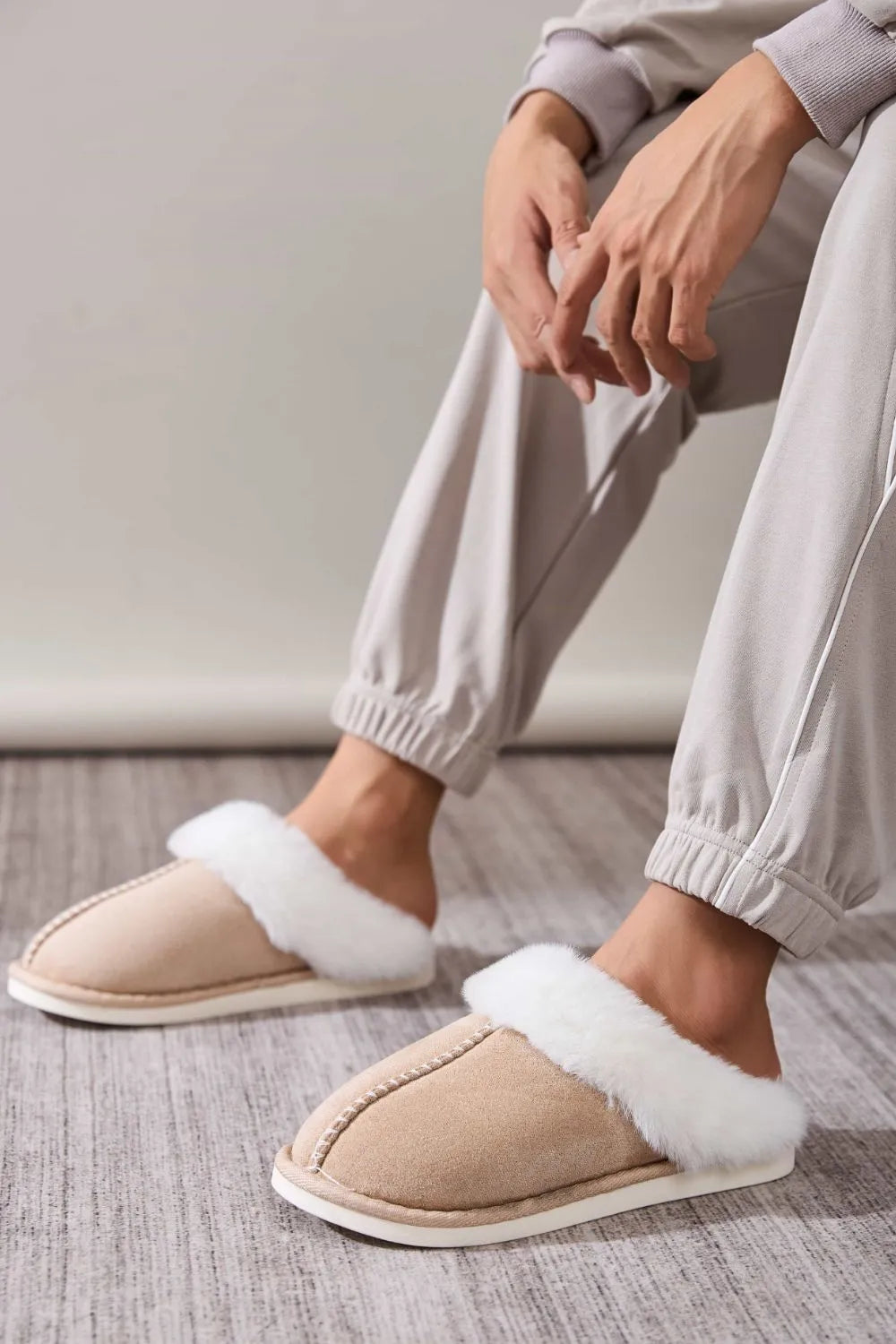 Beige suede house slides with white shearling trim and contrast stitching.