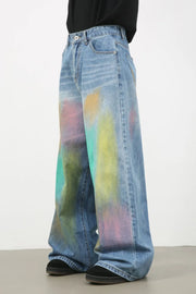 Graffiti wash wide leg denim trousers in medium blue with colorful paint splatters.
