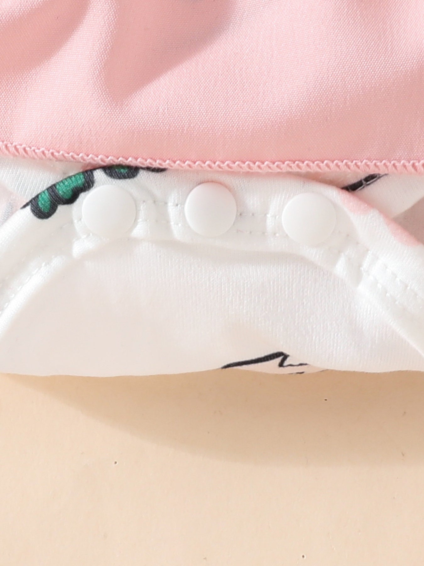 Baby dress with pink top, white bunny print, and snap closure detail.