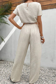 Beige textured crop top and wide-leg trousers set with a keyhole back detail.