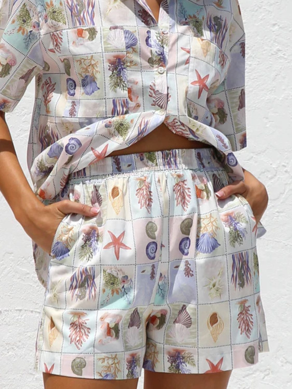 Resort set with short sleeve button-up shirt and elastic waist shorts in a pastel seashell print.