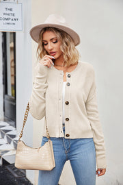 Cream textured knit cropped cardigan with buttons and round neckline.