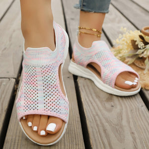 Pink open-toe knit sandals with white soles and an ankle cuff detail.