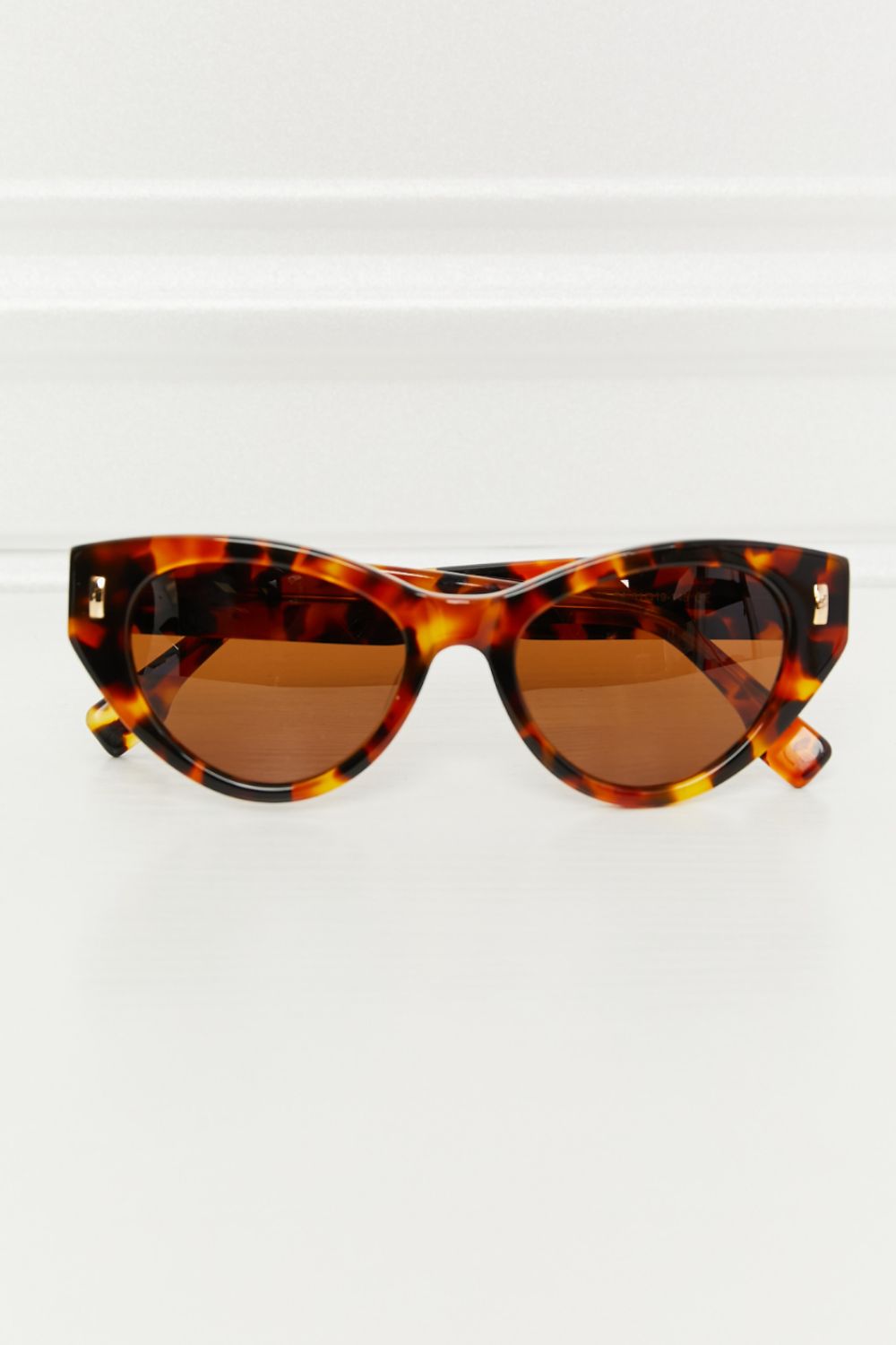 Cat-eye sunglasses in tortoise shell acetate with brown lenses and gold accents.