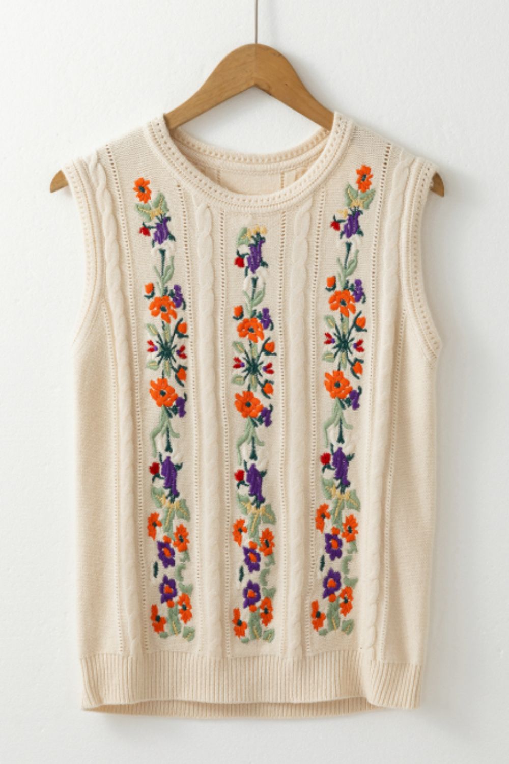 Beige cable knit vest with floral embroidery down the front.