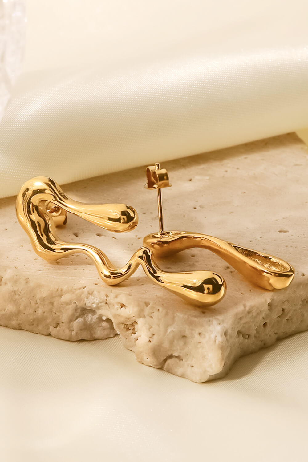 Gold asymmetrical drip earrings with a fluid, artistic design.
