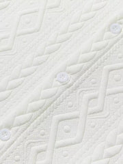 Off-white knit polo with textured geometric pattern and white buttons.