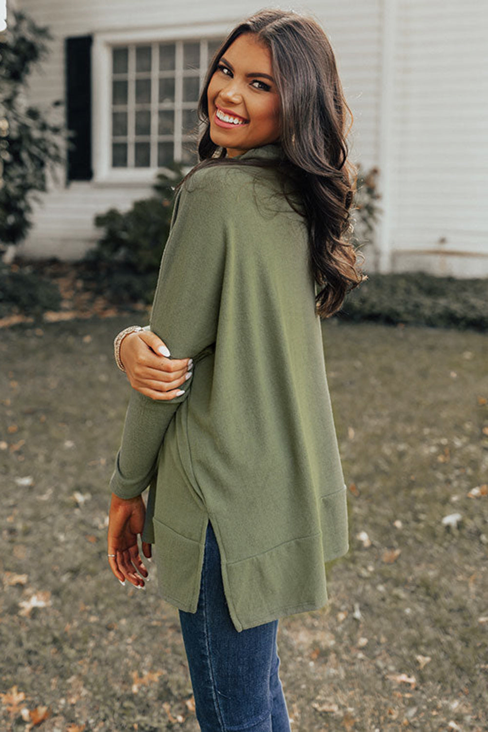 Army green tunic with cowl neckline, long sleeves, and side slits, styled with jeans.