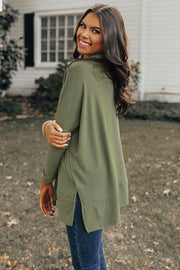 Army green tunic with cowl neckline, long sleeves, and side slits, styled with jeans.