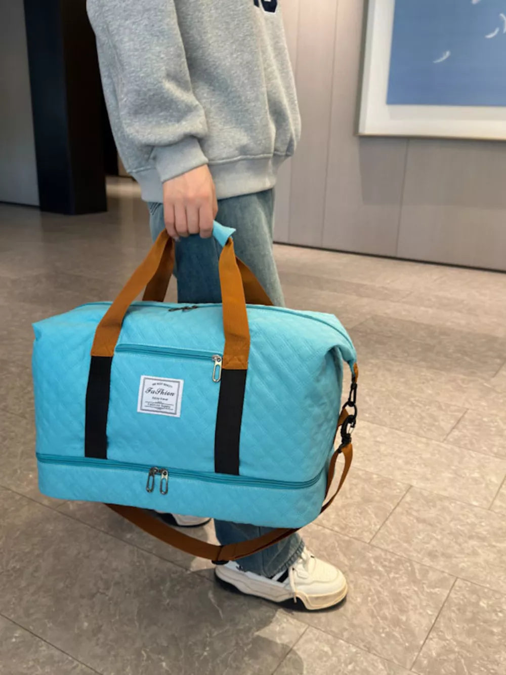 Luxurious quilted travel duffel bag in Lake Blue with brown straps and black accents.