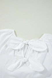White babydoll blouse with square neckline and two front bow details.