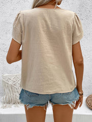 Tan linen blouse with puff sleeves and a relaxed fit, styled with denim shorts.