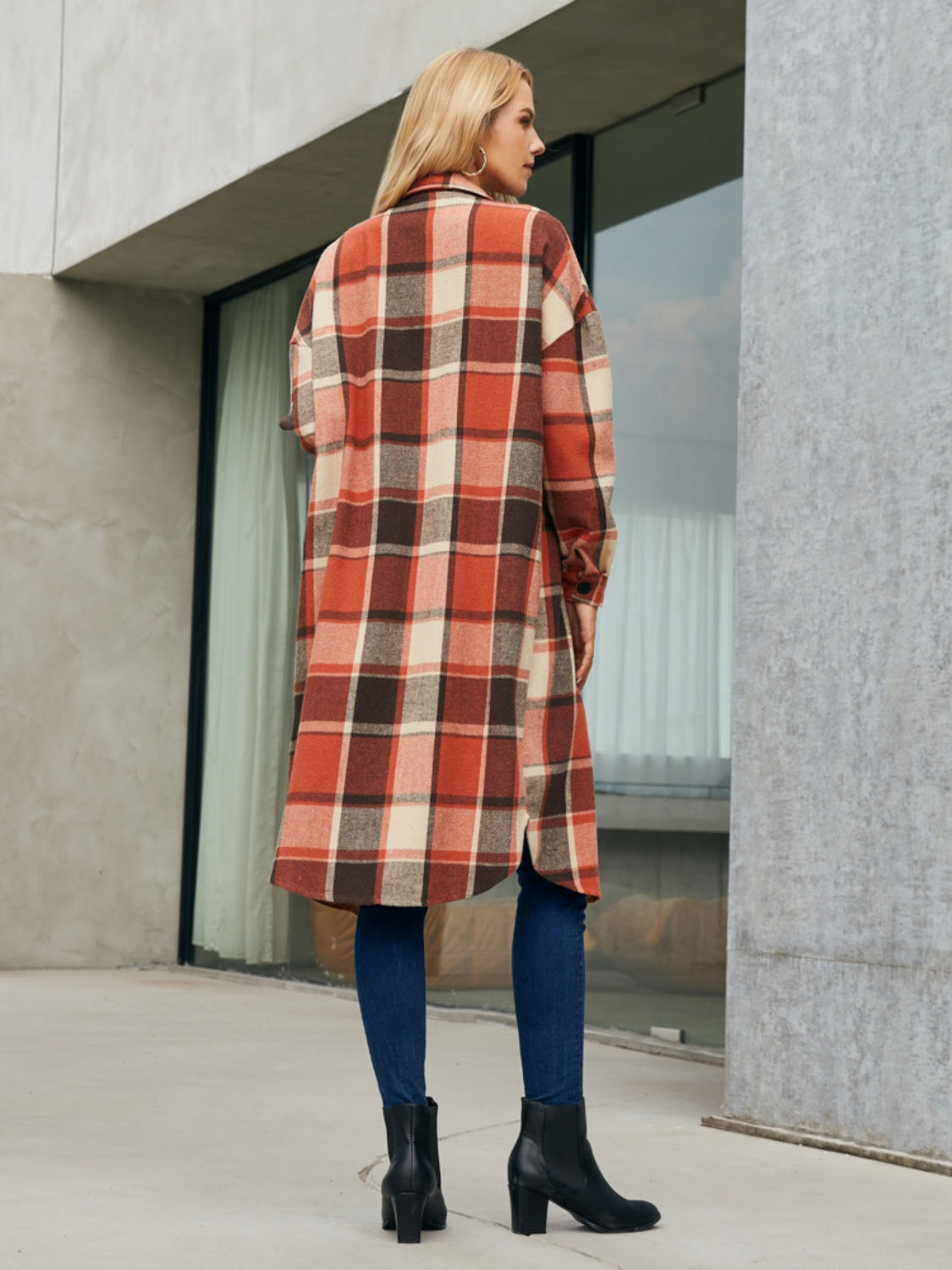 Oversized plaid shirt jacket dress in orange-red, brown, and cream, with button details and a long hem.