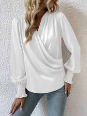 White ruched surplice blouse with bishop sleeves and smocked cuffs.