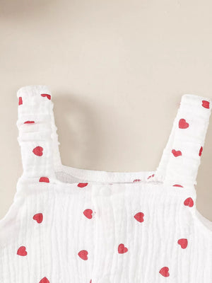 White baby romper with red hearts, ruffled straps, and button front.