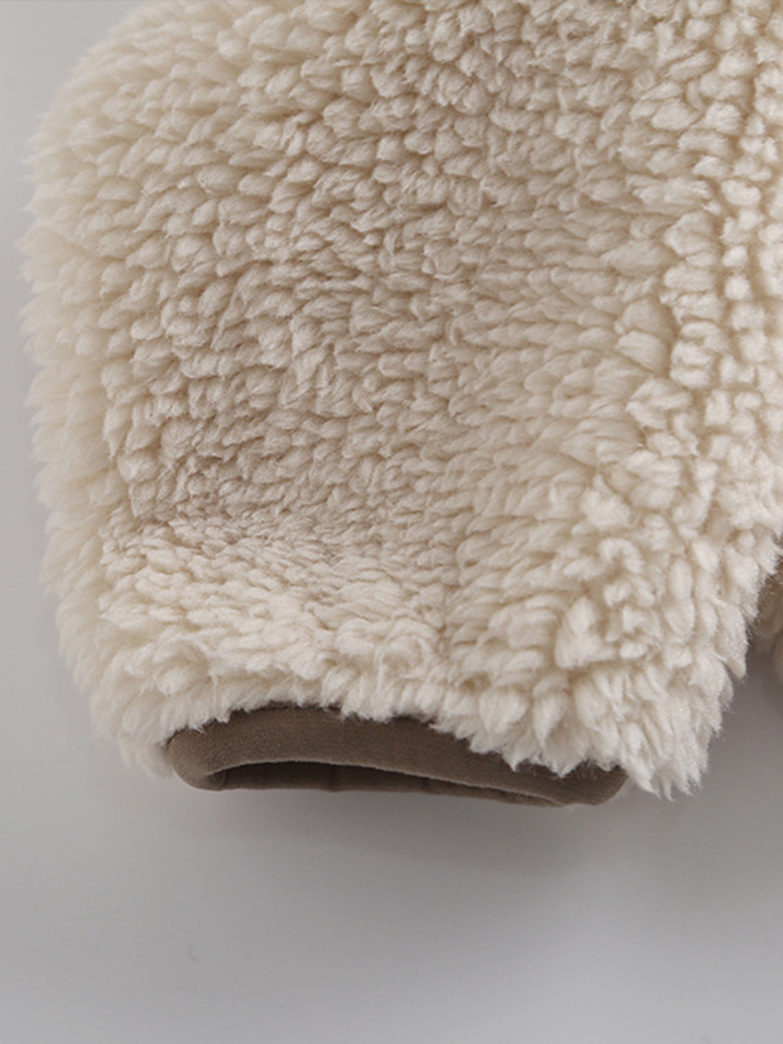 Beige sherpa zip-up jacket with brown trim detail.