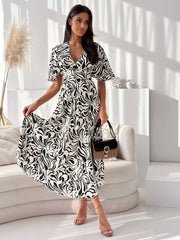 Midi dress with flutter sleeves, V-neck, and abstract black and white pattern.