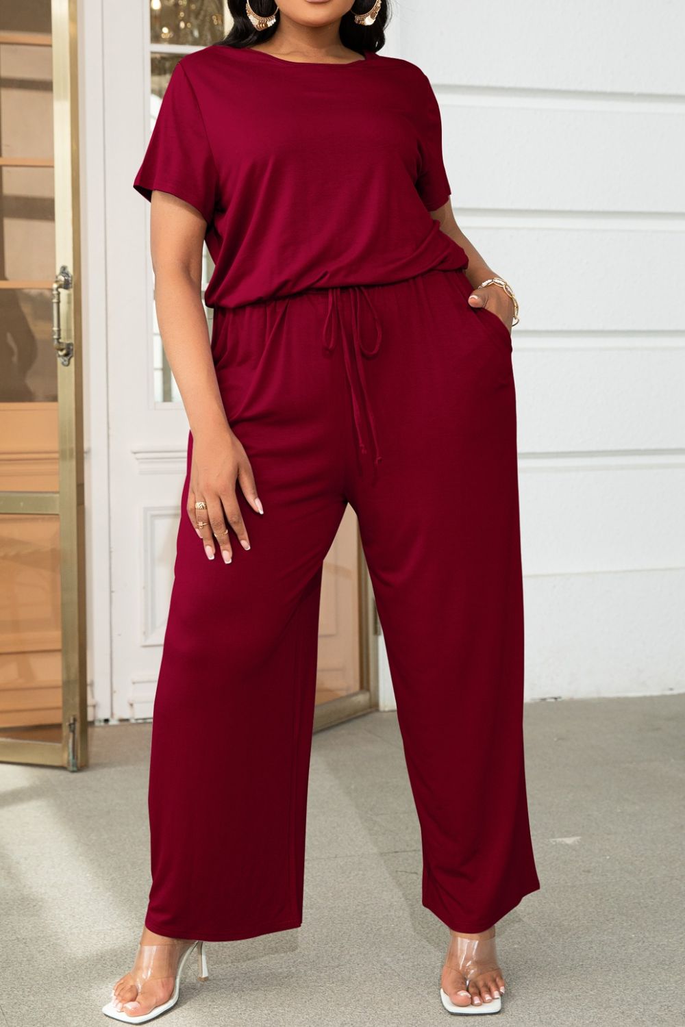 Wine relaxed fit jumpsuit with short sleeves, drawstring waist, and wide legs.