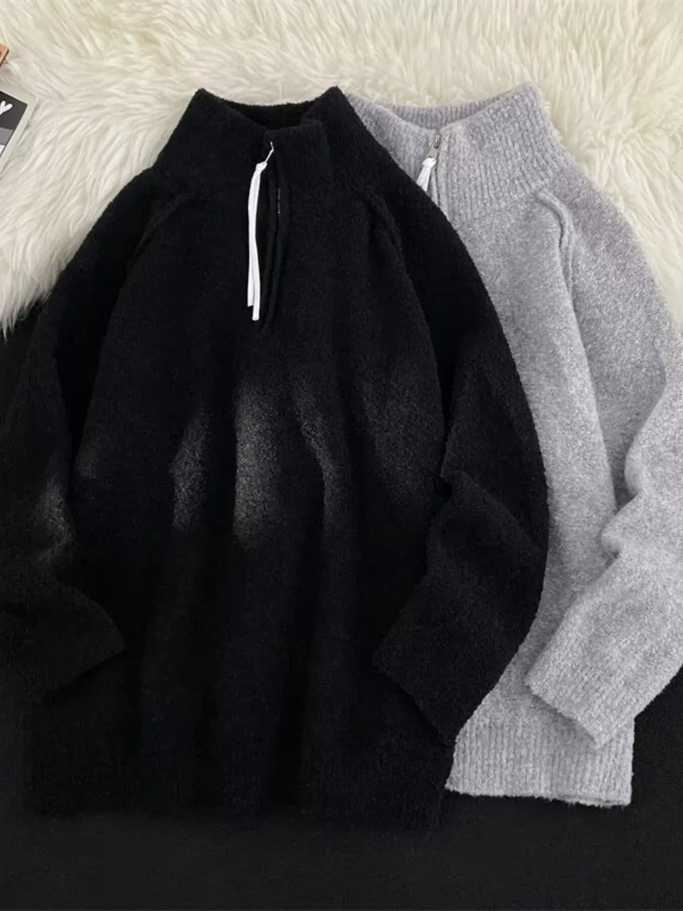Men's black and gray half-zip sweaters with high necks and textured fabric.