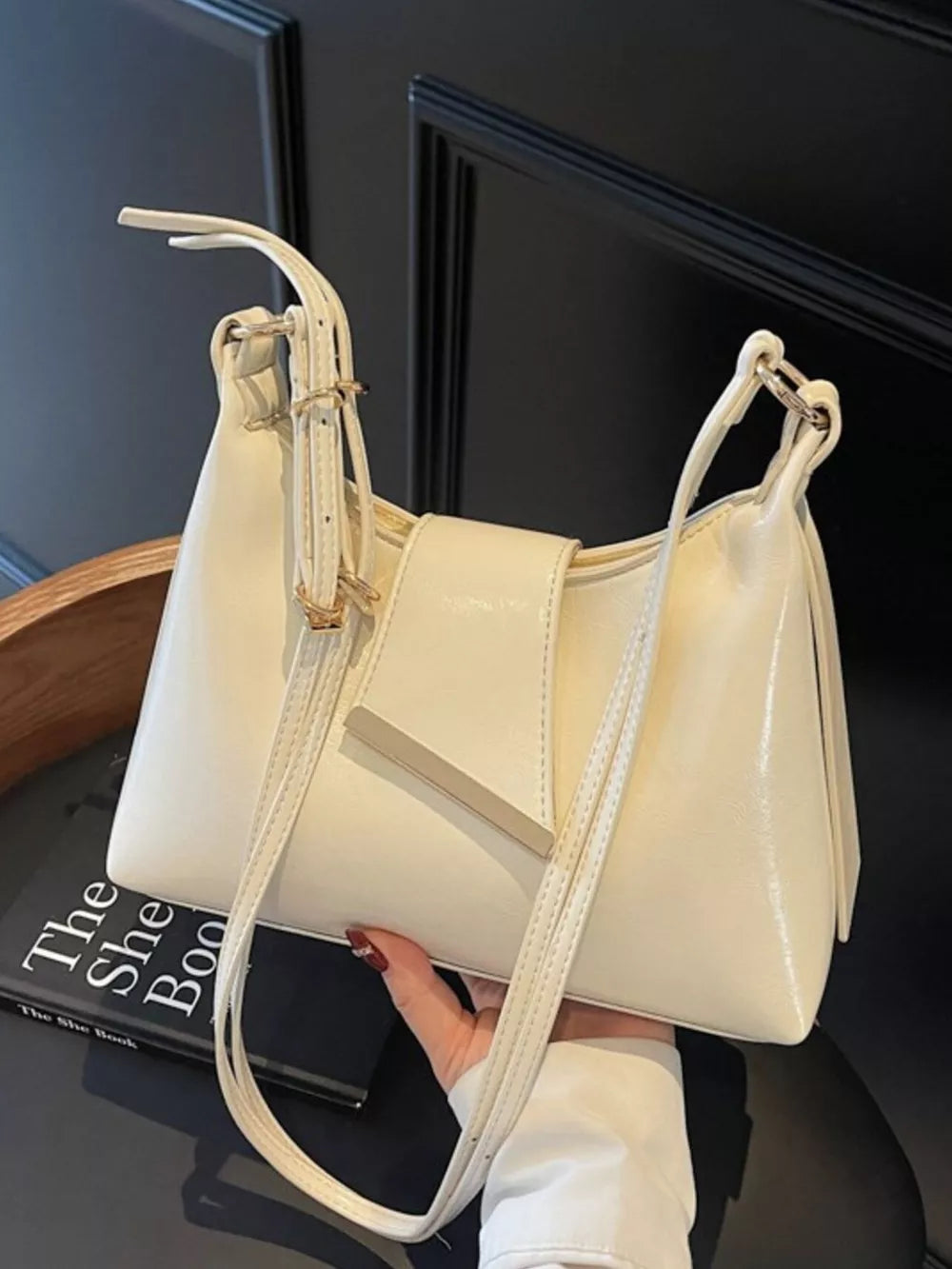 Beige crossbody bag with adjustable strap and gold hardware detail.