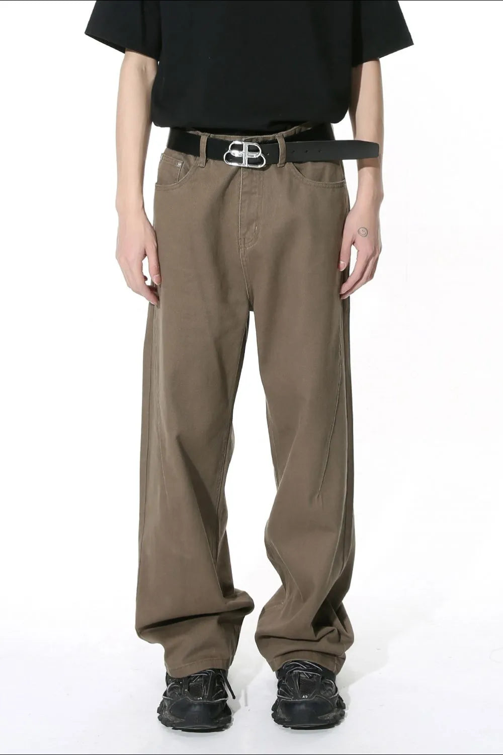 Brown wide-leg denim pants with angular seams and a black belt.