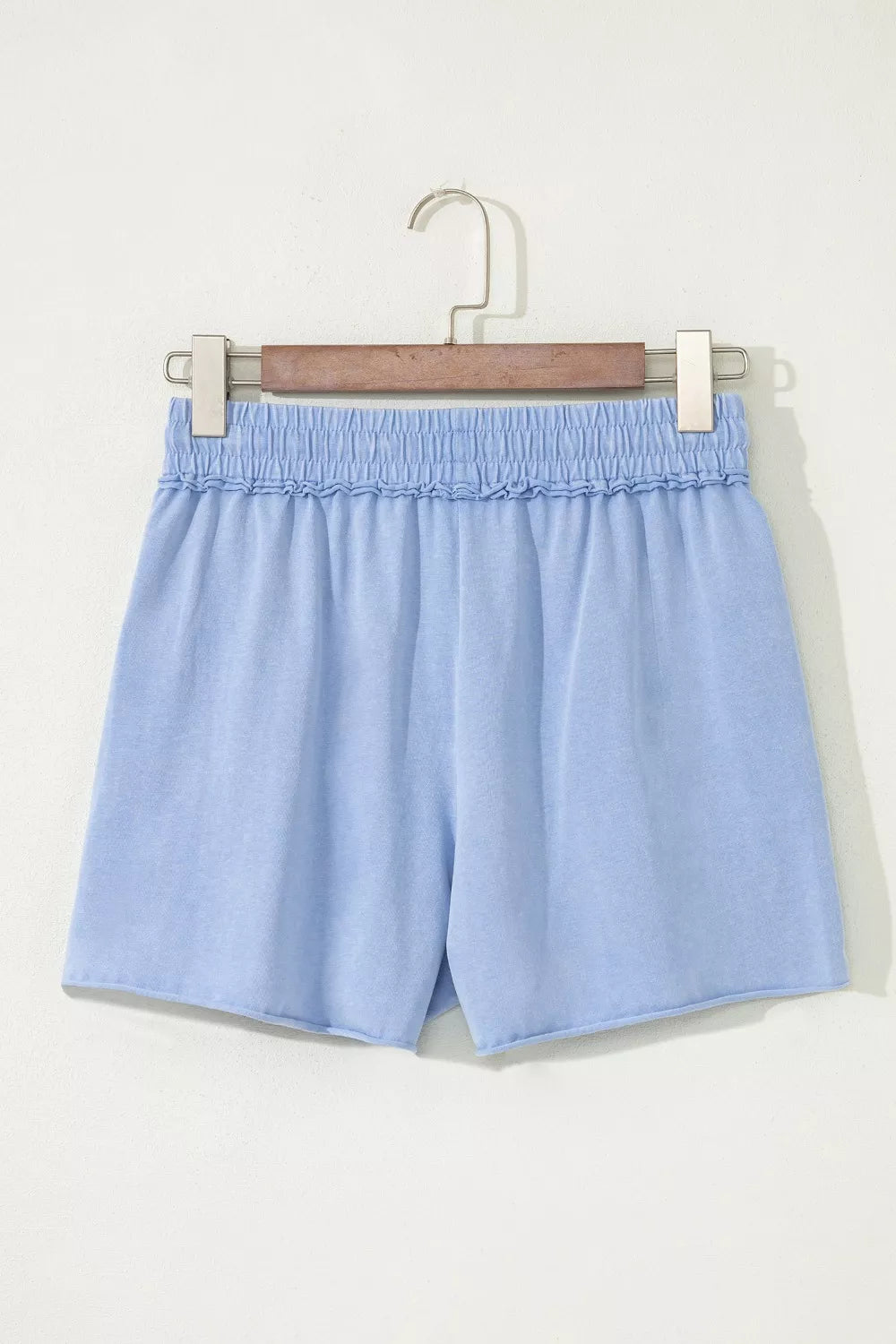 Light blue cotton drawstring shorts with ruffled elastic waistband and raw hem.