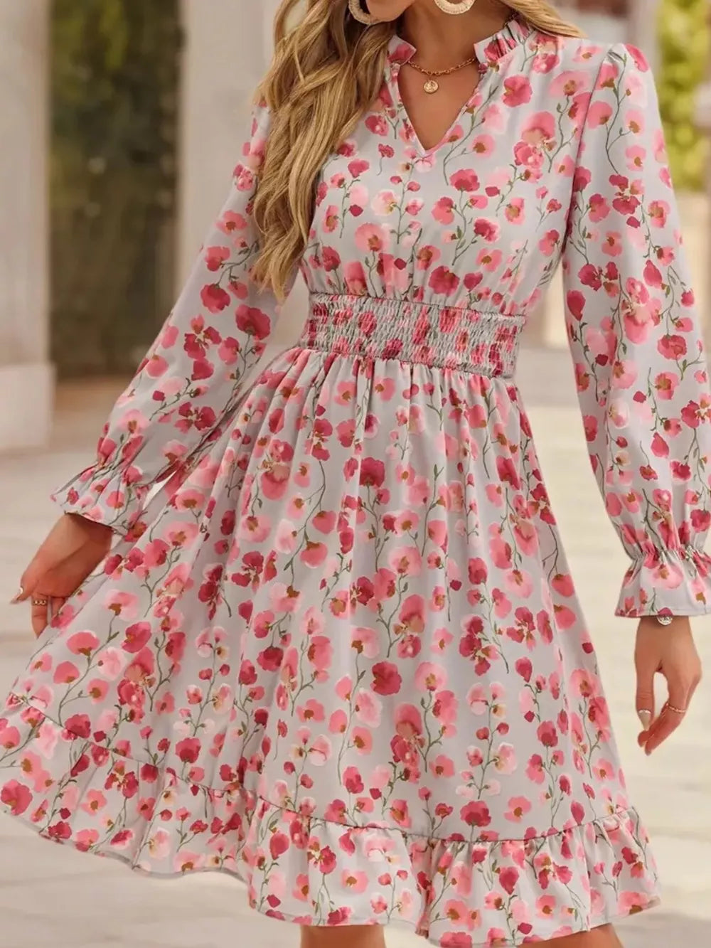 Romantic floral smocked dress in blush pink with ruffled cuffs and hem.