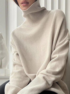 Relaxed turtleneck sweater in light beige acrylic with sculptural sleeves and ribbed cuffs.