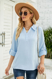 Light blue textured collared blouse with rolled sleeves and button placket.