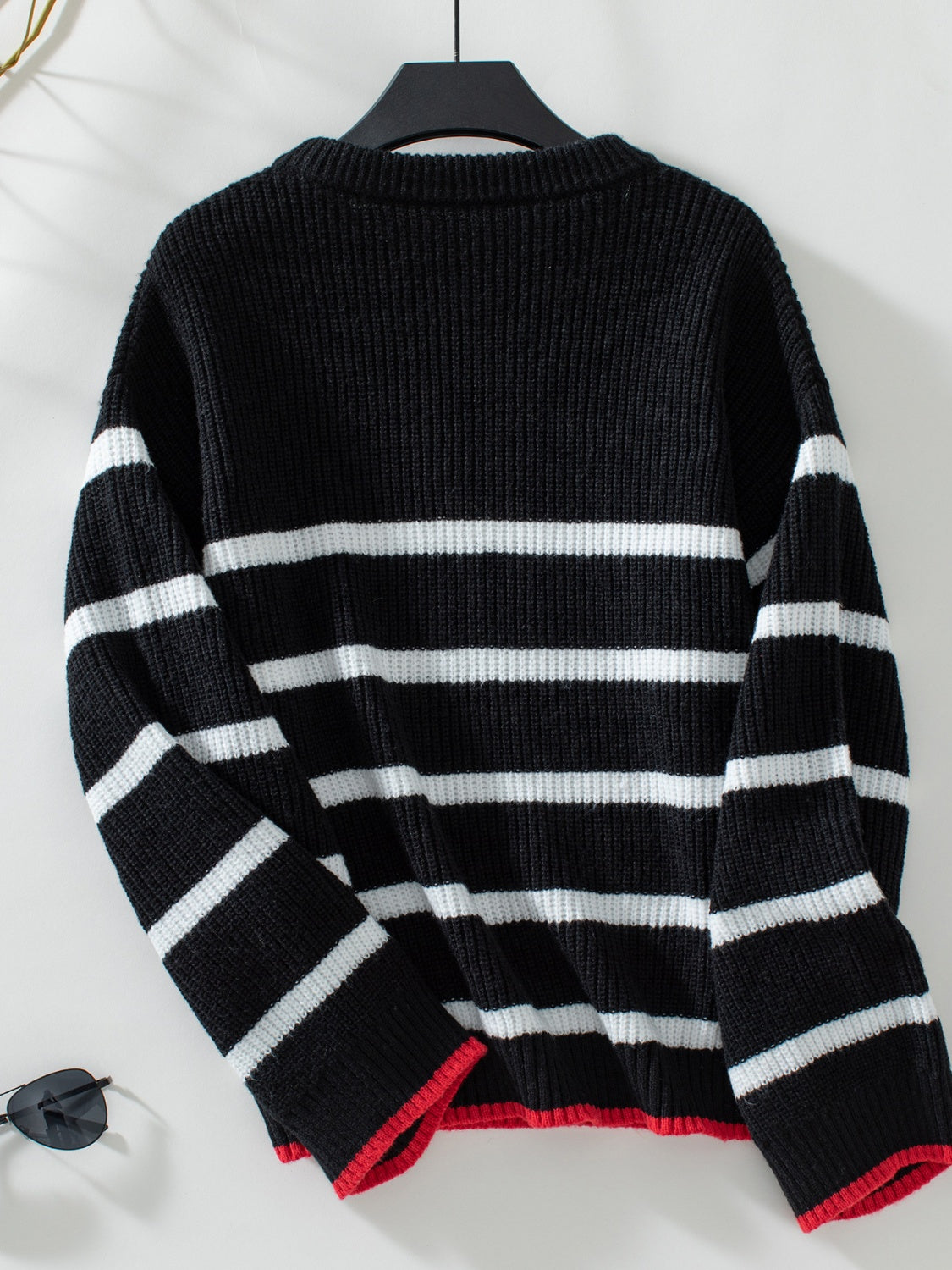 Black ribbed knit sweater with white stripes and red trim