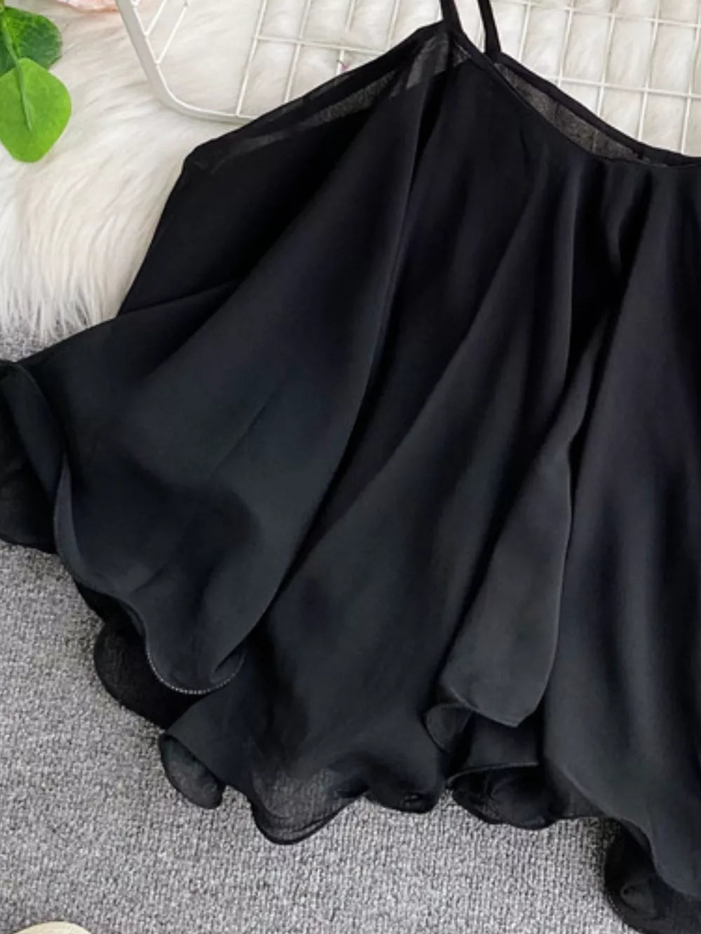 Black ruffled camisole with spaghetti straps and delicate hem detail